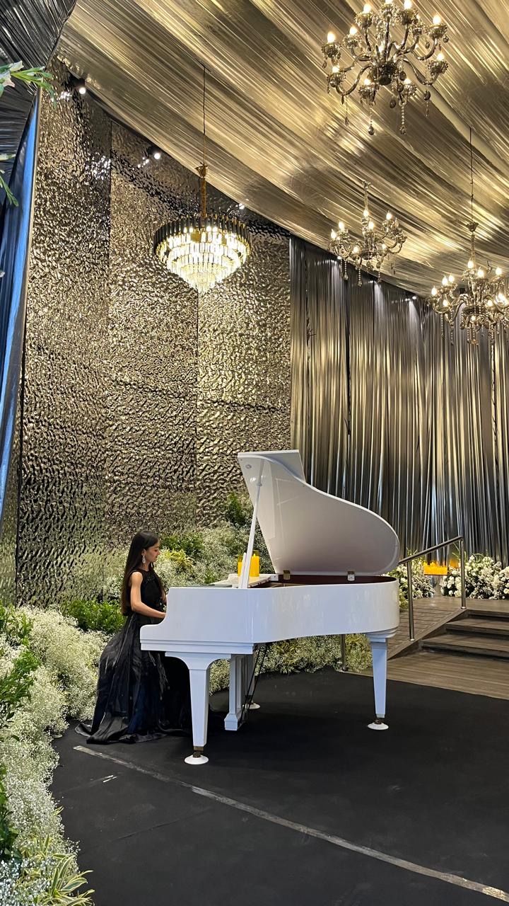Pianist at a white grand piano beneath crystal chandeliers