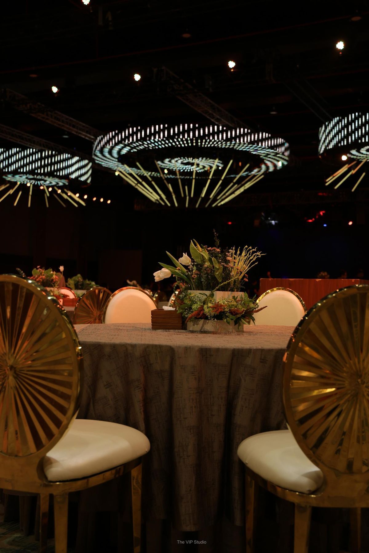 Gold sunburst chairs around a table under LED ring chandeliers