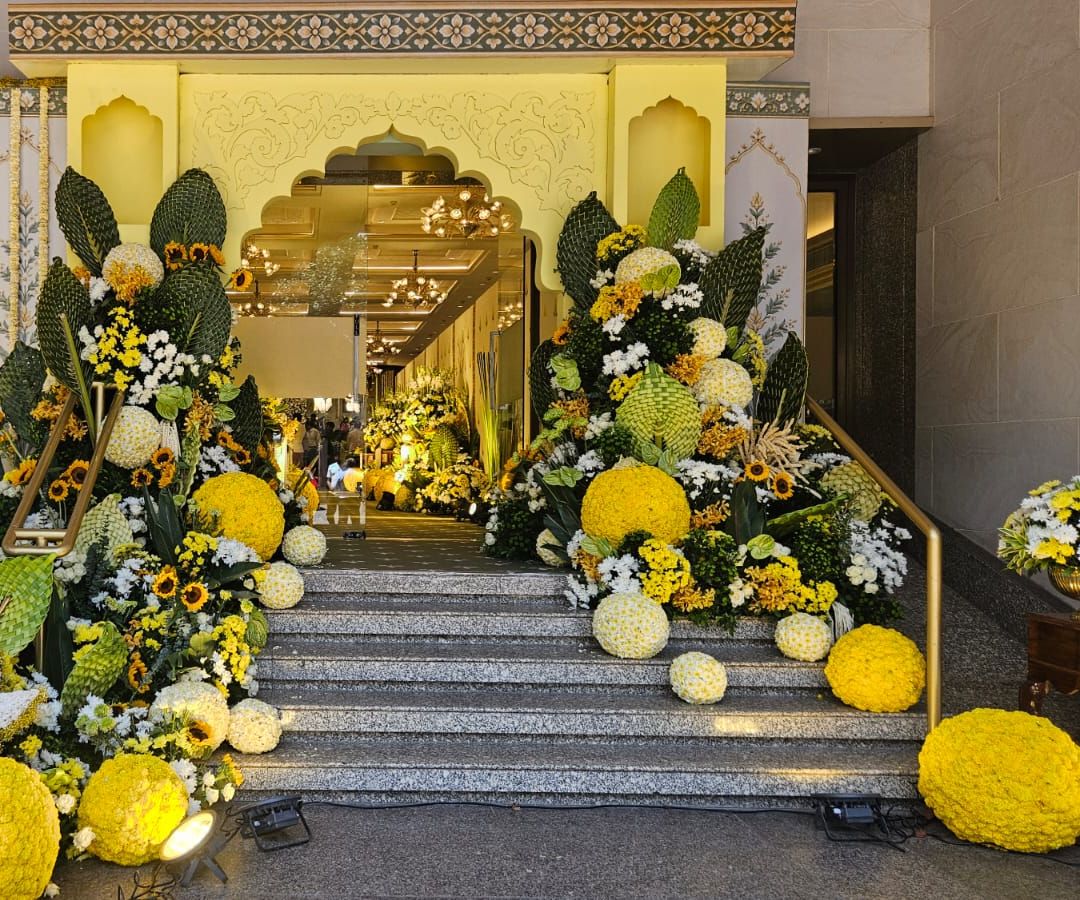 Yellow arched entrance flanked by sunflowers and chrysanthemum spheres